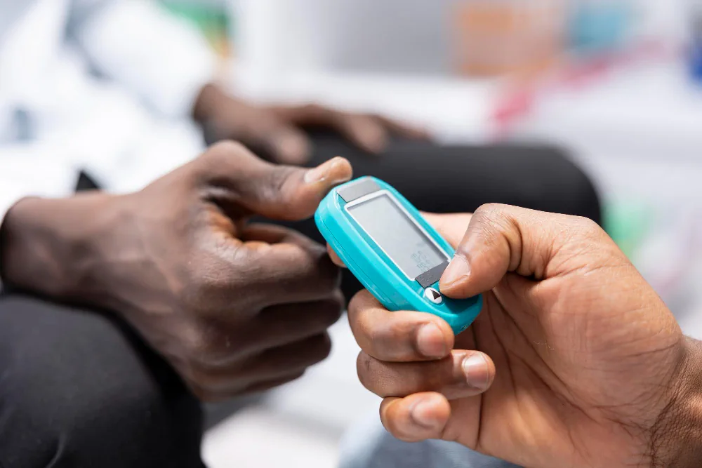 Handheld blood glucose meter being used to check a glucose reading