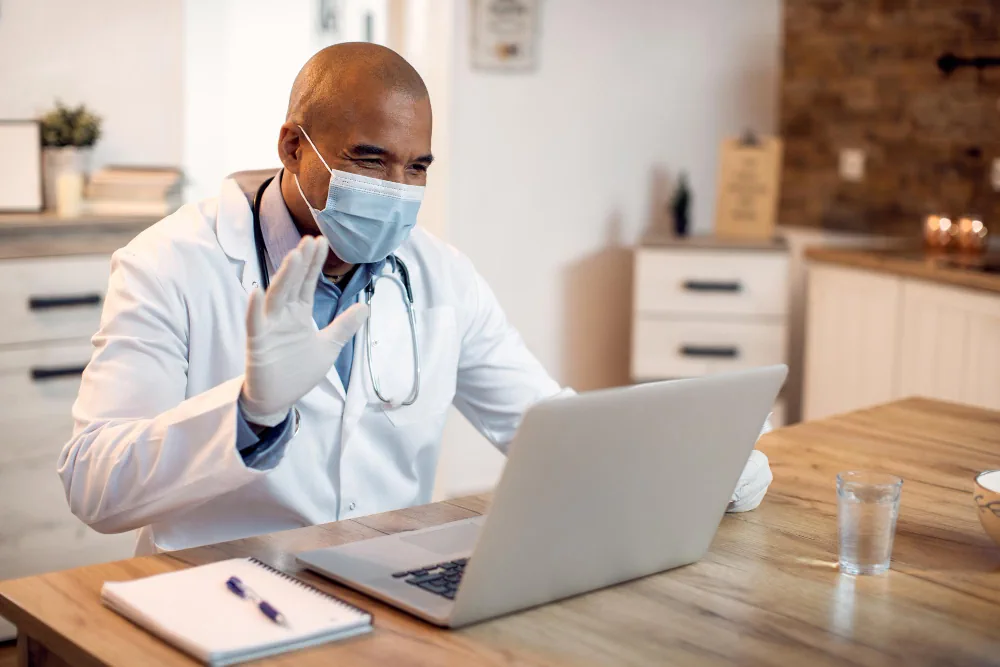 Healthcare provider using a laptop while reviewing ongoing patient care