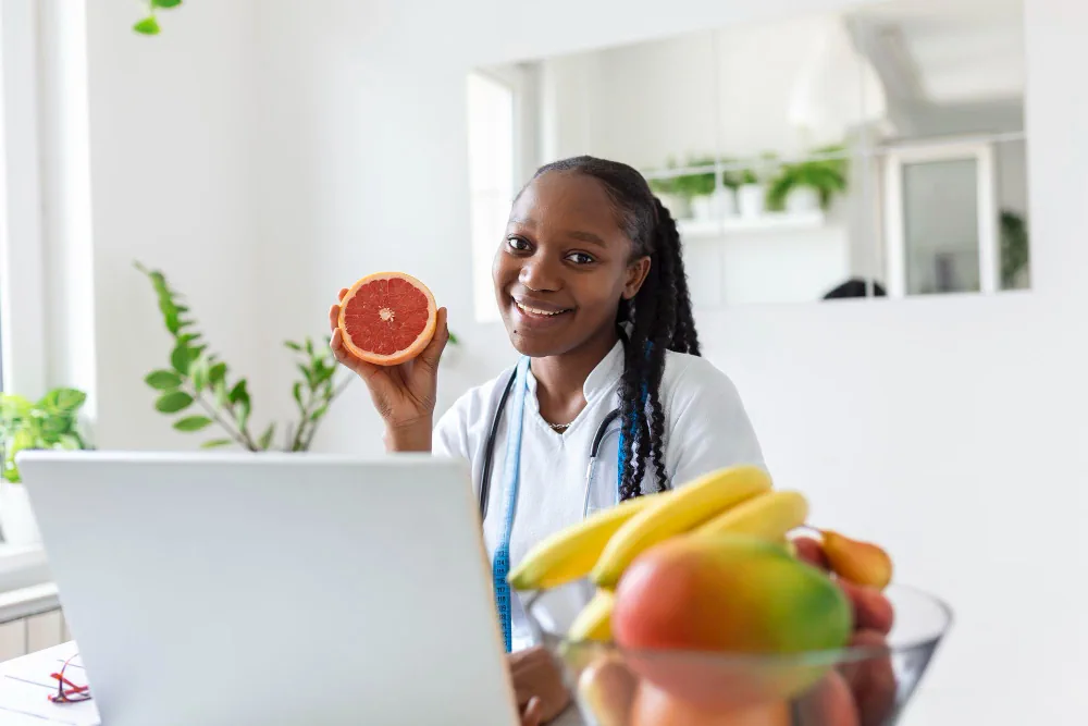 Woman holding healthy fruit during a virtual nutrition coaching session