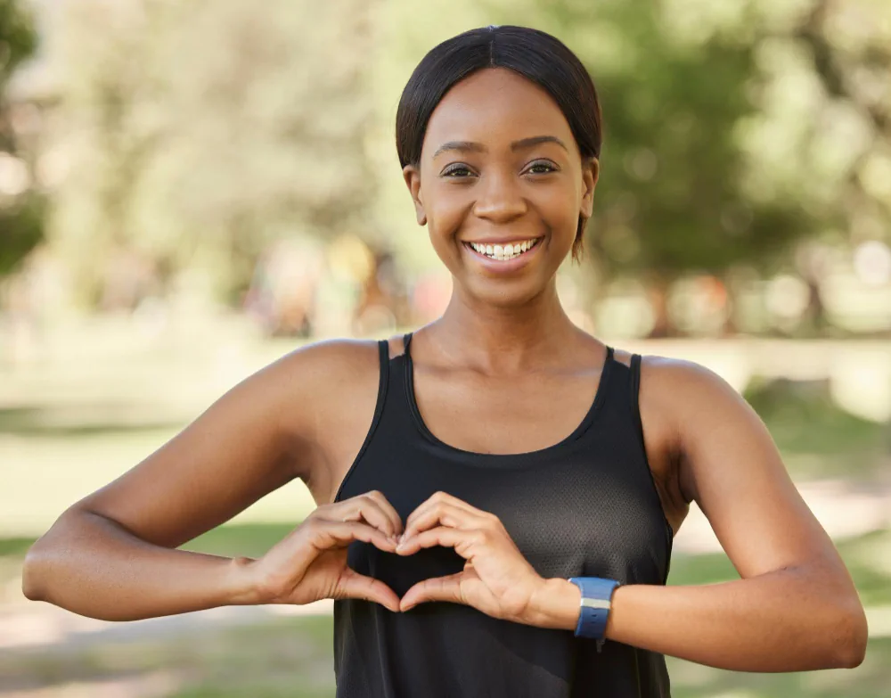 Woman making a heart shape with her hands representing health and wellbeing